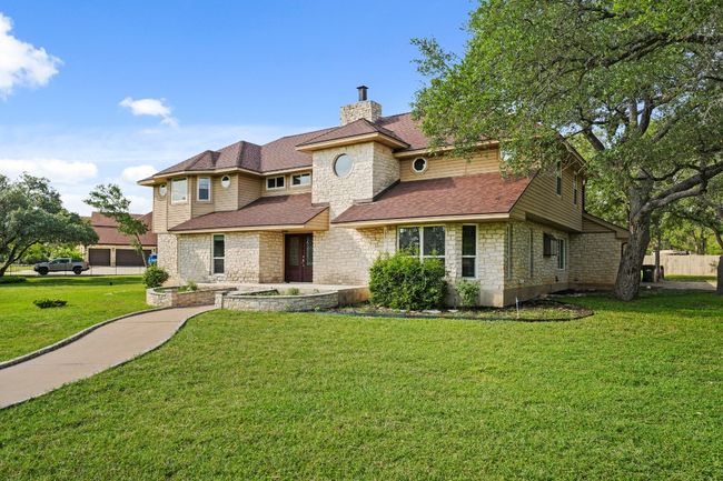 View of front of home with stone siding, a chimney, a front lawn, and a shingled roof | Image 35