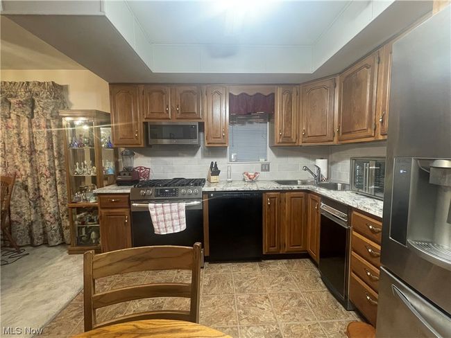 Kitchen featuring light tile flooring, a tray ceiling, stainless steel appliances, and tasteful backsplash | Image 15