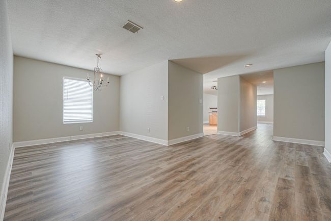 Spare room featuring a chandelier, plenty of natural light, a textured ceiling, light wood-style flooring, and recessed lighting | Image 4