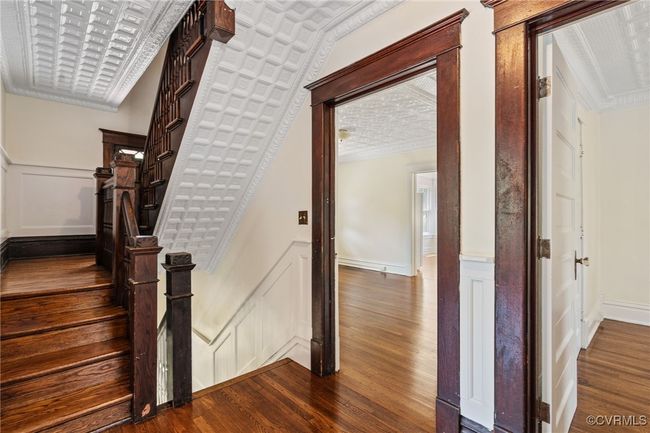 Stairway featuring a decorative wall, wood finished floors, a wainscoted wall, and crown molding | Image 25