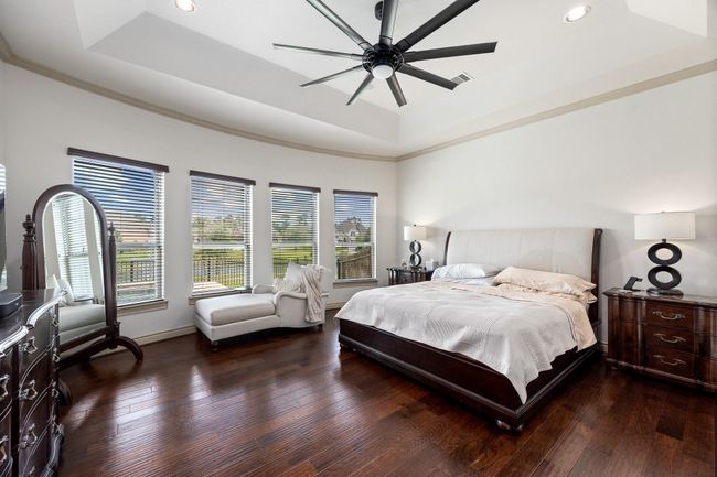 Welcome to the first flor master suite. The incredible space offers a tray ceiling, wood floors, and amazing views of the pool and community lake. | Image 21