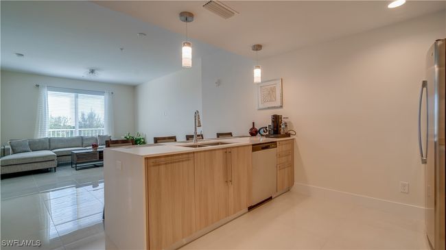 Kitchen featuring kitchen peninsula, light brown cabinets, appliances with stainless steel finishes, pendant lighting, and sink | Image 13