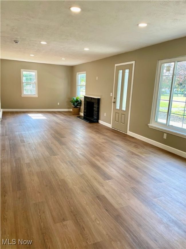 Unfurnished living room featuring a fireplace, plenty of natural light, wood finished floors, and recessed lighting | Image 10