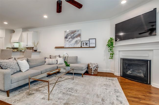 Living room with crown molding, wood finished floors, recessed lighting, a glass covered fireplace, and ceiling fan | Image 9