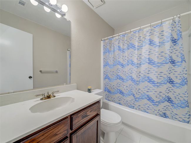 Bathroom with toilet, vanity, tile patterned flooring, and shower / bath combination with curtain | Image 22