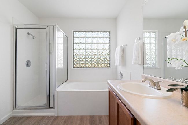 The primary ensuite features dual vanities, a garden tub, a separate walk-in shower and plenty of natural light thanks to the glass block window above the bathtub. | Image 24