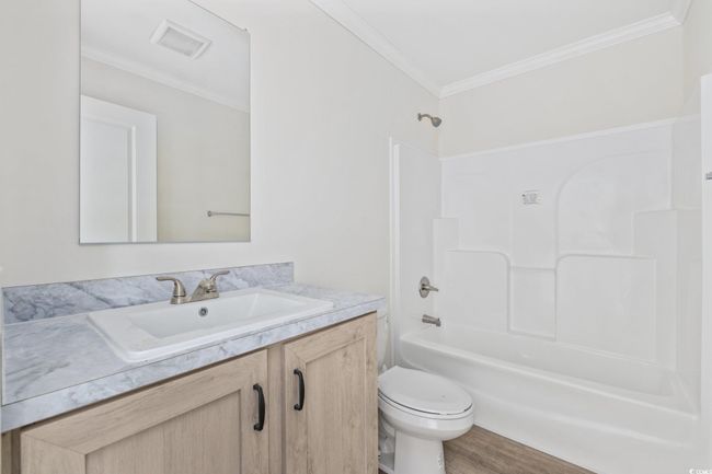Full bathroom with vanity, shower / bath combination, crown molding, and wood finished floors | Image 25