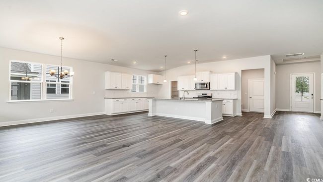 Kitchen with hanging light fixtures, dark hardwood / wood-style flooring, white cabinets, sink, and a center island with sink | Image 21