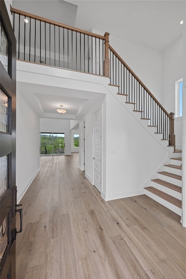 Foyer entrance featuring wood finished floors, stairs, a high ceiling, baseboards, and a fireplace | Image 19
