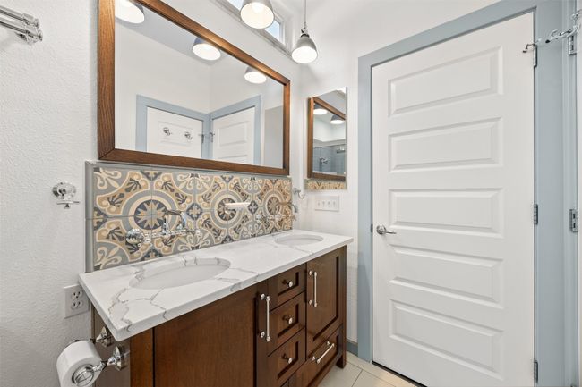 Full bath featuring double vanity, tasteful backsplash, and tile patterned floors | Image 19