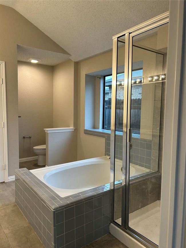 Bathroom with a garden tub, a stall shower, vaulted ceiling, a textured ceiling, and tile patterned flooring | Image 13