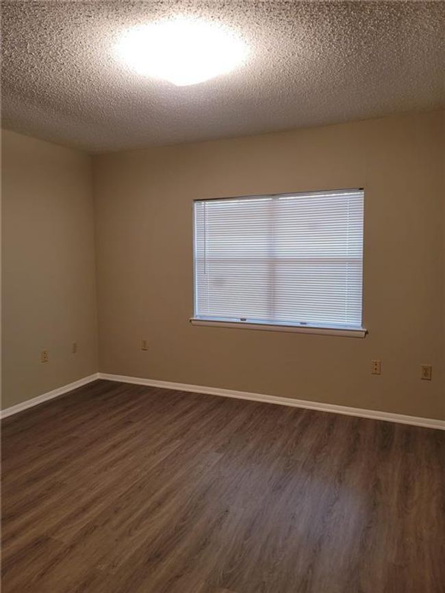 Empty room with dark wood-style floors and a textured ceiling | Image 13