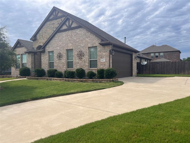 View of side of property featuring brick siding, driveway, an attached garage, and a shingled roof | Image 4