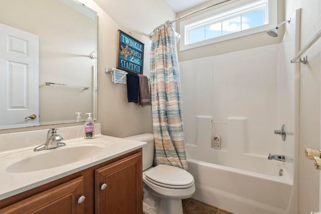 Full bathroom featuring tile patterned floors, shower / bathtub combination with curtain, toilet, and vanity | Image 18