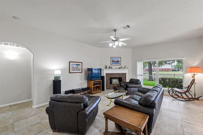 Amazing living room features gorgeous tile flooring, high ceilings, ceiling fan, surround sound system and a beautiful wood burning and natural gas fireplace. | Image 4
