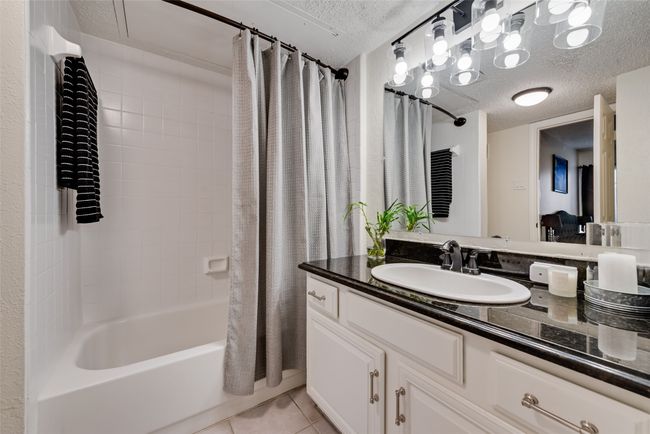 Full bath featuring a textured ceiling, shower / bathtub combination with curtain, vanity, and tile patterned flooring | Image 15