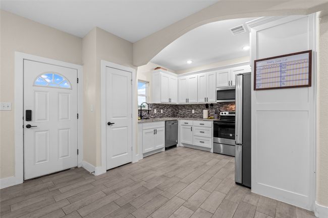 Kitchen with stainless steel appliances, arched walkways, tasteful backsplash, white cabinets, and recessed lighting | Image 21