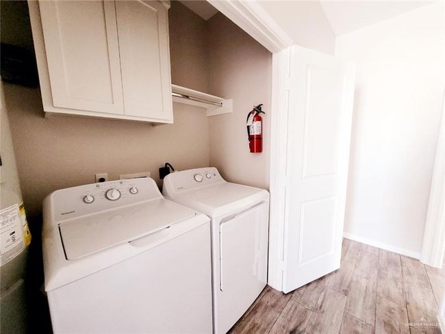 Laundry room featuring washing machine and clothes dryer, cabinet space, and baseboards | Image 12