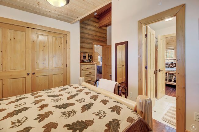 Bedroom featuring rustic walls, a closet, a wooden ceiling with exposed beams, and wood finished floors | Image 26