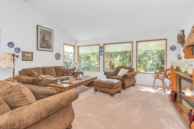 Living area featuring light carpet, a glass covered fireplace, and lofted ceiling | Image 12