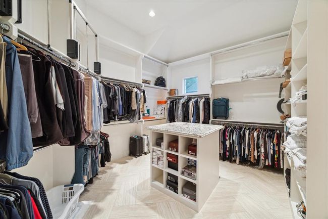 This spacious walk-in closet features ample hanging space, shelving, and a central island with storage, offering a well-organized and luxurious dressing area. | Image 18