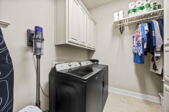 Laundry room featuring washer and clothes dryer, cabinet space, baseboards, and light tile patterned floors | Image 19