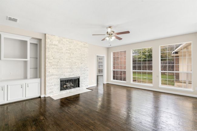 Unfurnished living room featuring visible vents, baseboards, a fireplace, wood finished floors, and a ceiling fan | Image 17