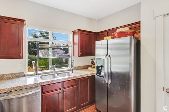Kitchen with appliances with stainless steel finishes, dark brown cabinets, light stone counters, and wood finished floors | Image 13