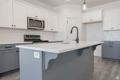 Kitchen with gray cabinets, pendant lighting, an island with sink, and stainless steel appliances | Image 3