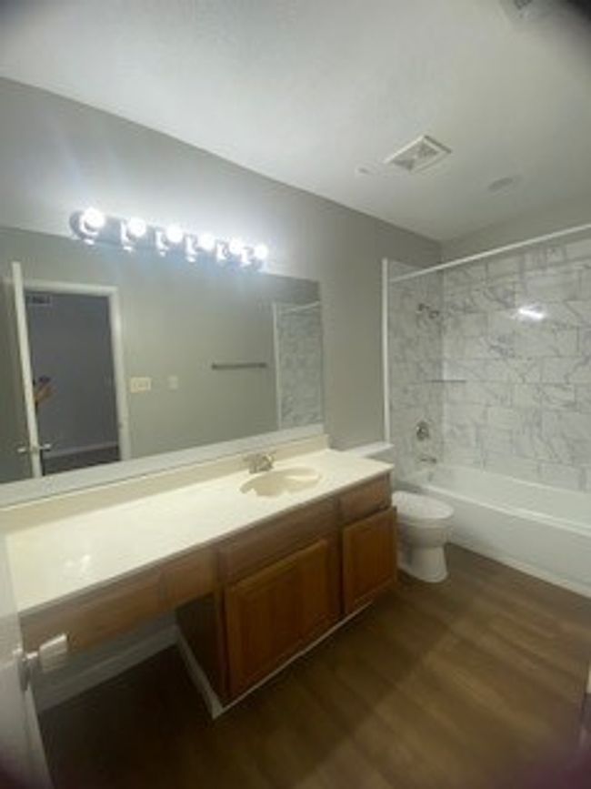 Full bathroom featuring wood finished floors, vanity, washtub / shower combination, and toilet | Image 21