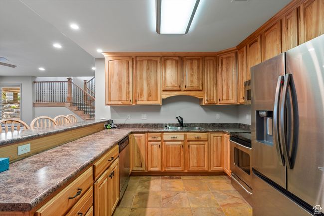 Kitchen with appliances with stainless steel finishes, a sink, recessed lighting, light stone finish floors, and a ceiling fan | Image 59