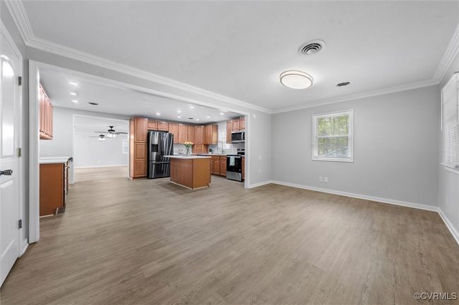 Kitchen featuring appliances with stainless steel finishes, light countertops, baseboards, open floor plan, and light wood-type flooring | Image 6