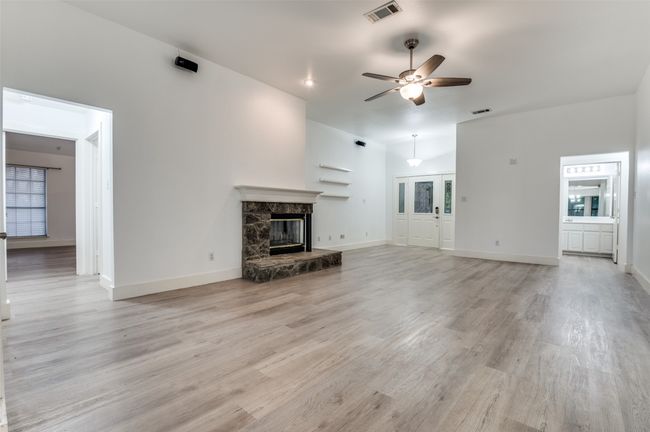 Unfurnished living room with ceiling fan, a fireplace, and light wood-style flooring | Image 6