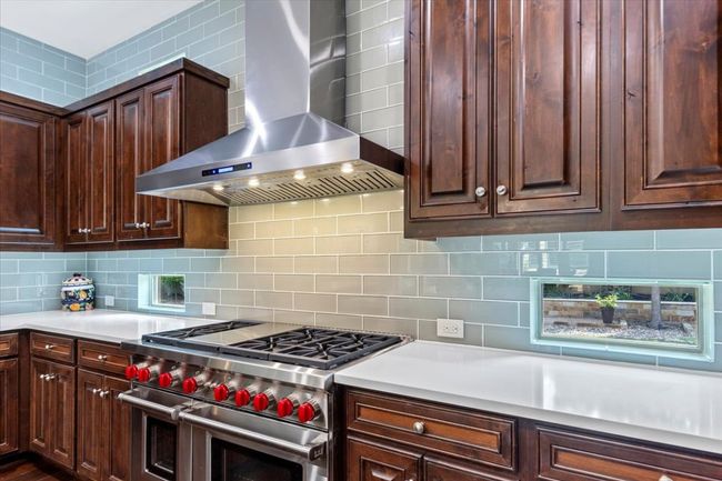 Kitchen with wall chimney range hood, double oven range, and decorative backsplash | Image 12