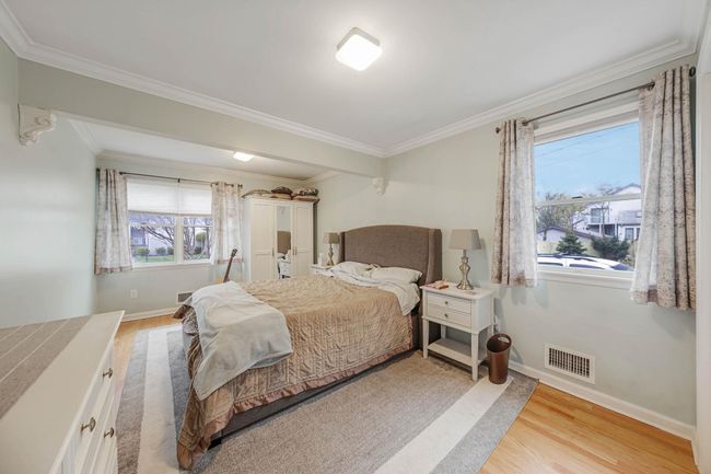 Bedroom with baseboards, light wood-style flooring, visible vents, and ornamental molding | Image 30
