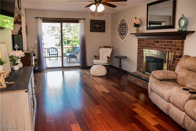 Living room featuring a ceiling fan, dark wood finished floors, and a brick fireplace | Image 23