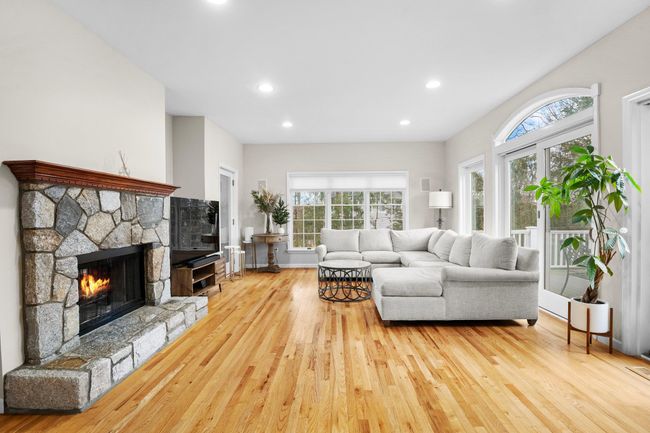Gather around the stunning stone fireplace in this warm and inviting family room with gleaming hardwood floors. | Image 12