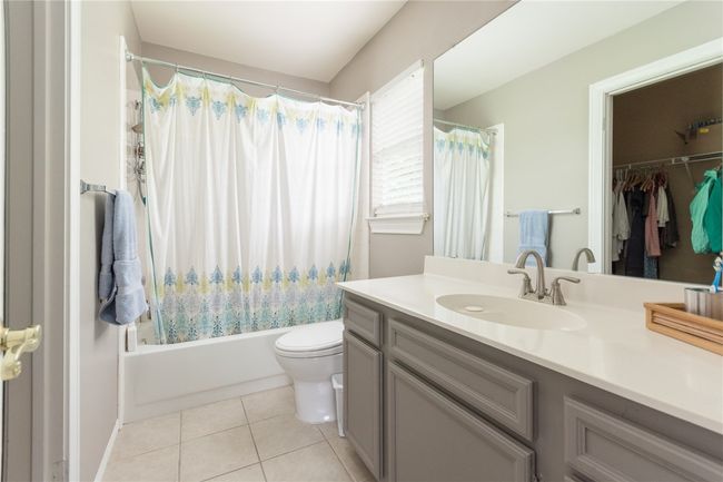 Bathroom with vanity, shower / bath combination with curtain, tile patterned flooring, and a walk in closet | Image 26