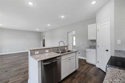 Kitchen with stainless steel dishwasher, white cabinetry, sink, dark hardwood / wood-style floors, and a center island with sink | Image 3