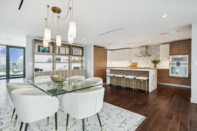 The contemporary and well-designed kitchen features Poggenpohl soft-close cabinetry, Gaggenau appliances and a calacatta waterfall marble island and backsplash. The kitchen can accommodate a crowd with island seating for 4 and a large breakfast room. | Image 12