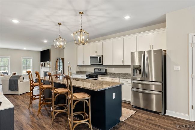 Kitchen featuring pendant lighting, a kitchen island with sink, white cabinets, dark hardwood / wood-style floors, and stainless steel appliances | Image 28
