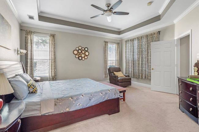 Carpeted bedroom with a tray ceiling, crown molding, and a ceiling fan | Image 21