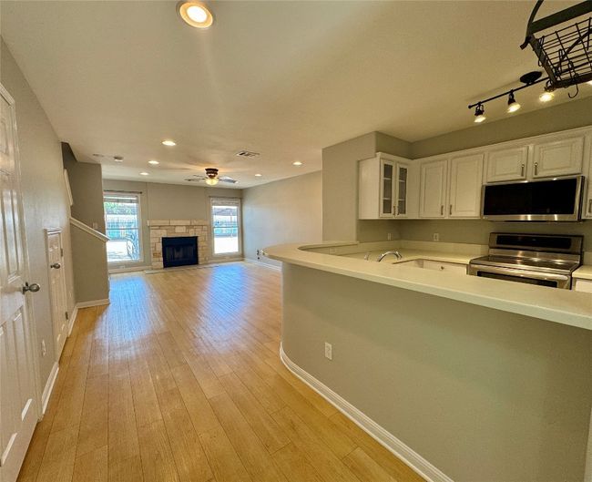 Kitchen featuring stainless steel appliances, white cabinetry, light countertops, glass insert cabinets, and recessed lighting | Image 11