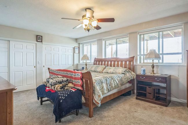 Bedroom featuring carpet flooring, multiple windows, multiple closets, and a ceiling fan | Image 39