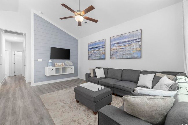 Living area featuring wood finished floors, visible vents, a ceiling fan, baseboards, and high vaulted ceiling | Image 4