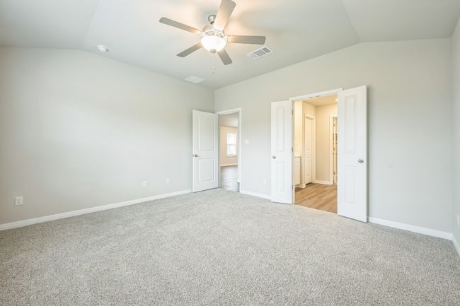 Unfurnished bedroom with vaulted ceiling, light colored carpet, and ceiling fan | Image 13