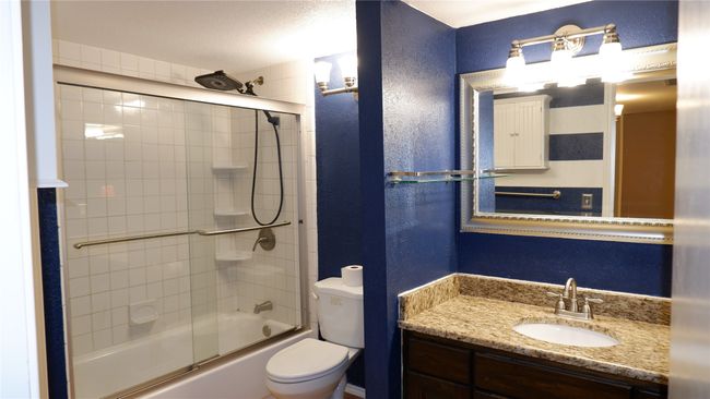 Full bathroom featuring combined bath / shower with glass door, toilet, a textured ceiling, and vanity | Image 13