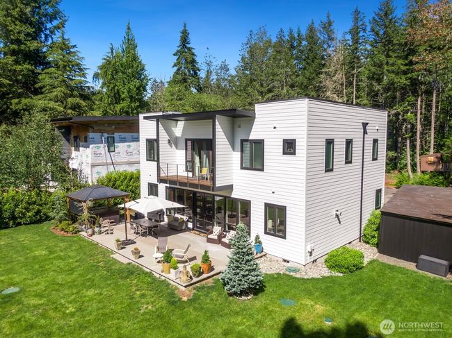 Another view of this wooded lot shows the large shed on the right side, and treehouse in the background. The siding and roof of the home are brand-new for added peace of mind. | Image 38