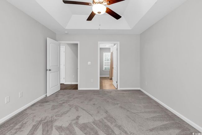Unfurnished bedroom featuring a tray ceiling, carpet flooring, baseboards, and a ceiling fan | Image 25