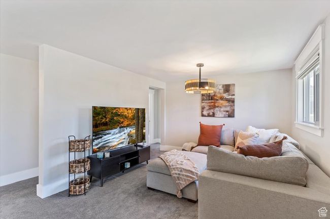 Carpeted living room featuring a chandelier and baseboards | Image 7